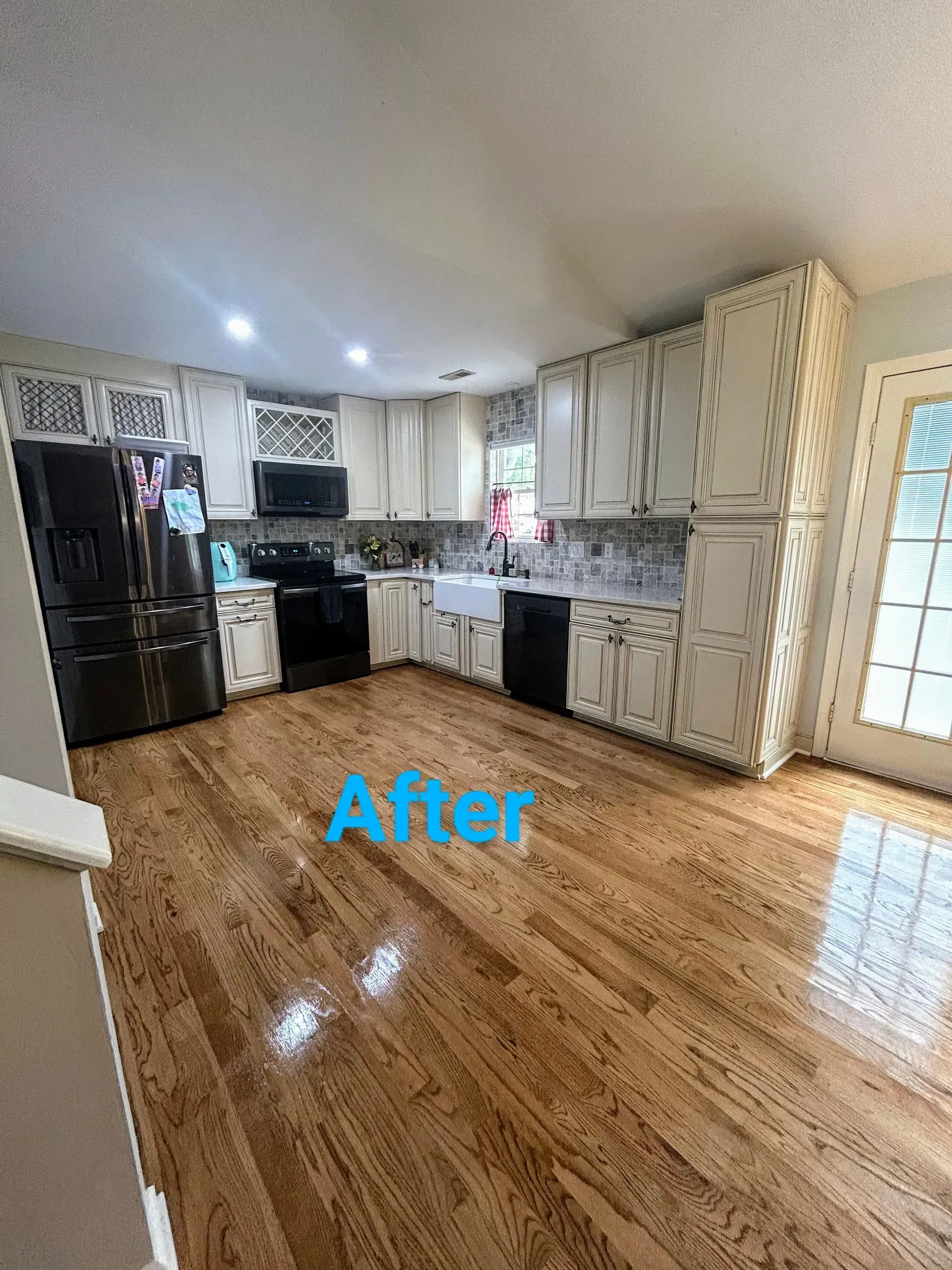 Newly renovated kitchen with wood floors, white cabinets, black appliances.