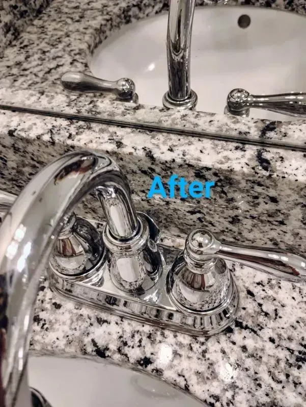 Close-up of a shiny chrome bathroom faucet on a granite countertop; 