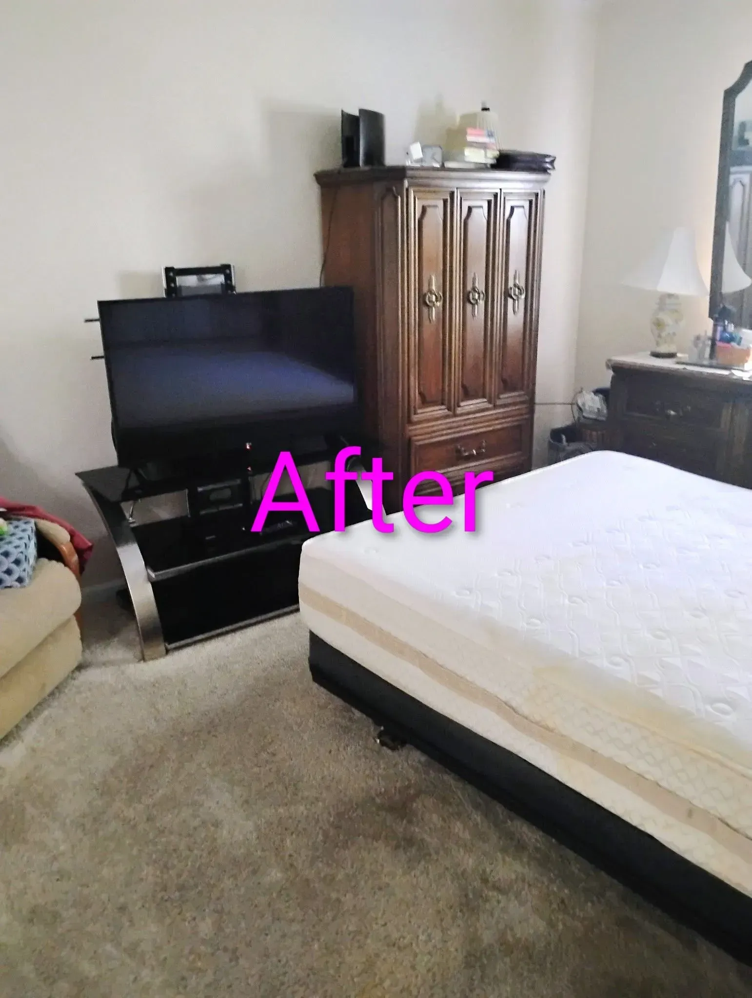 Bedroom with TV on stand, wooden wardrobe, unmade bed, and beige carpet.