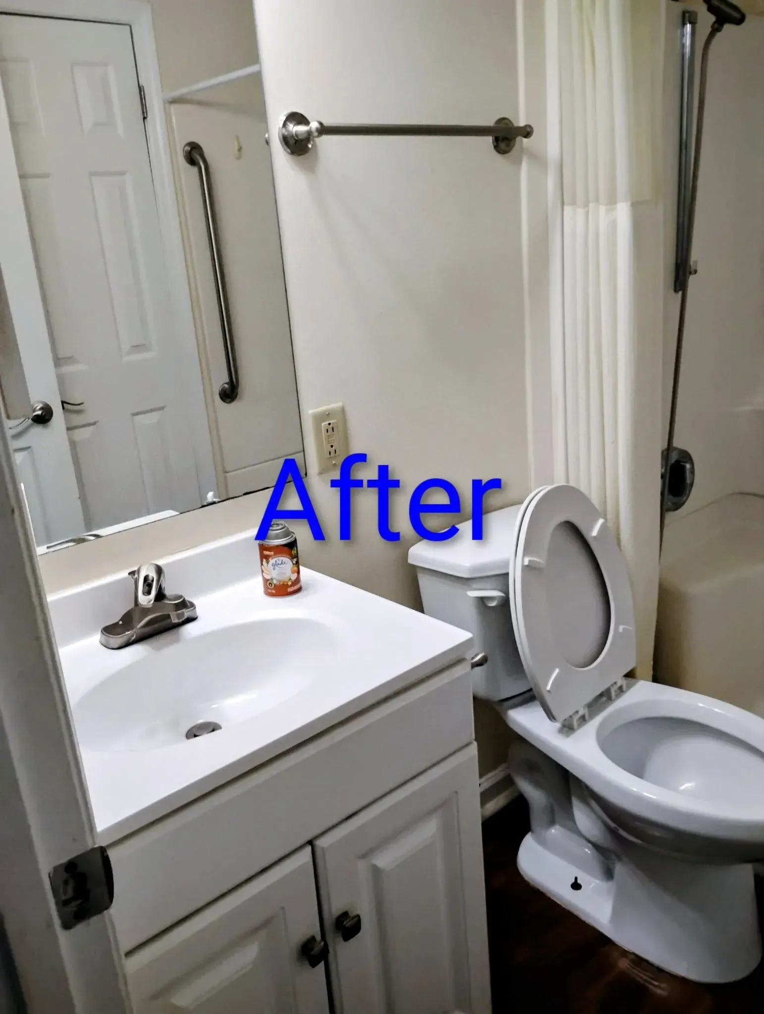 Bathroom with white vanity, toilet, and shower/tub.  Mirror, grab bar, towel rack visible.