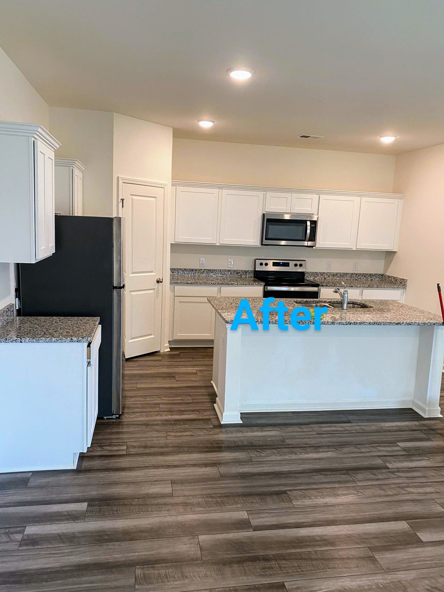 White kitchen with dark gray appliances, speckled countertops, and wood floors.