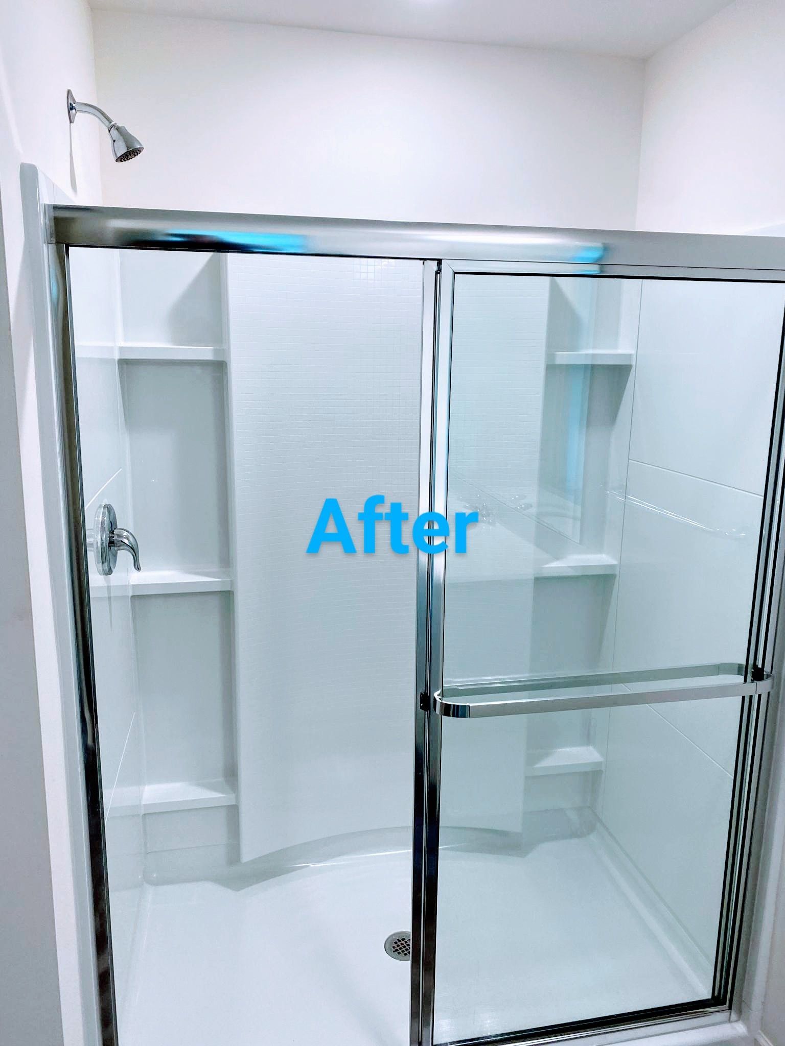 Bright white shower with sliding glass doors, chrome fixtures, and built-in shelves. 
