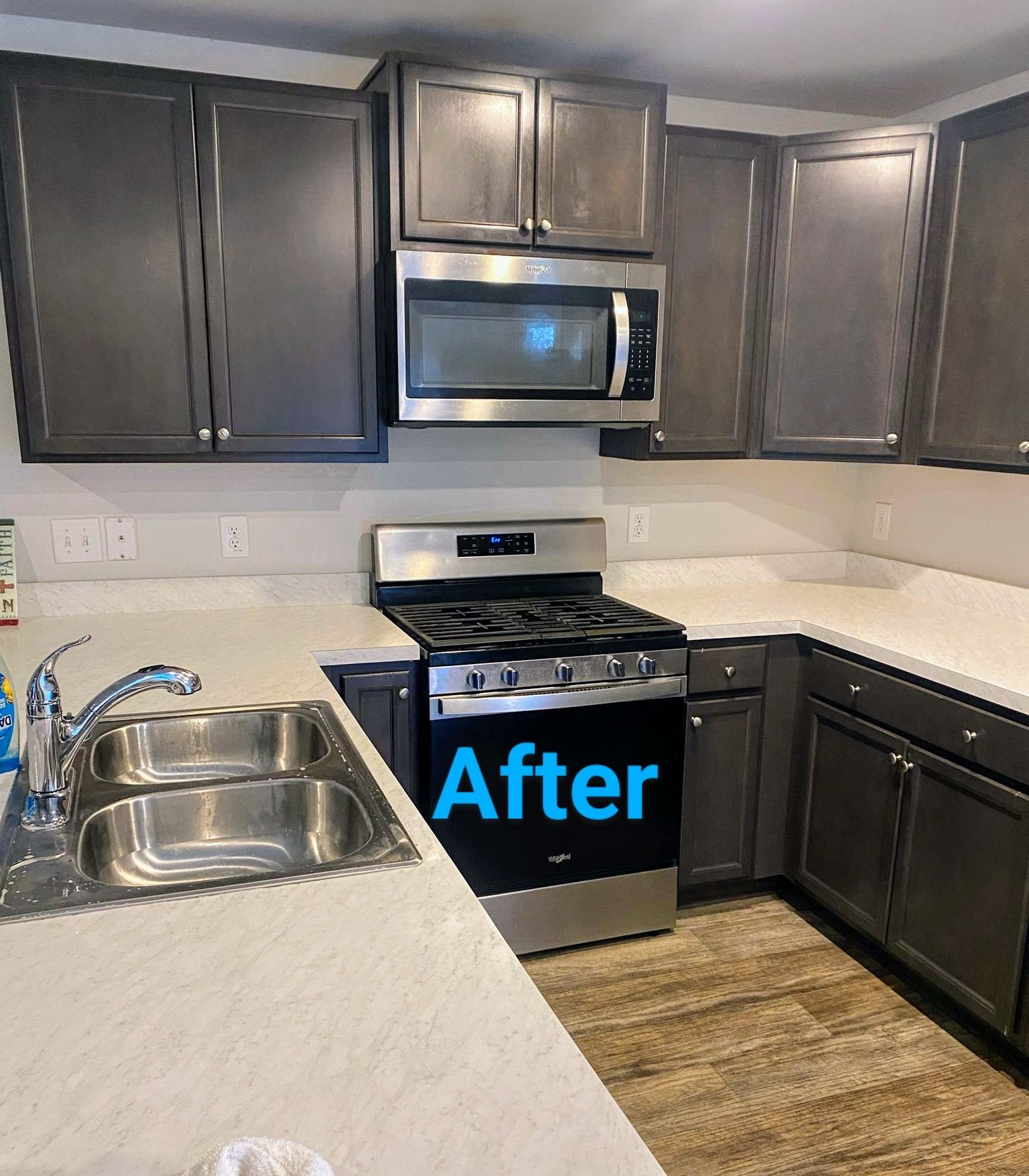 Gray kitchen cabinets with white countertops and a stainless steel stove and microwave.