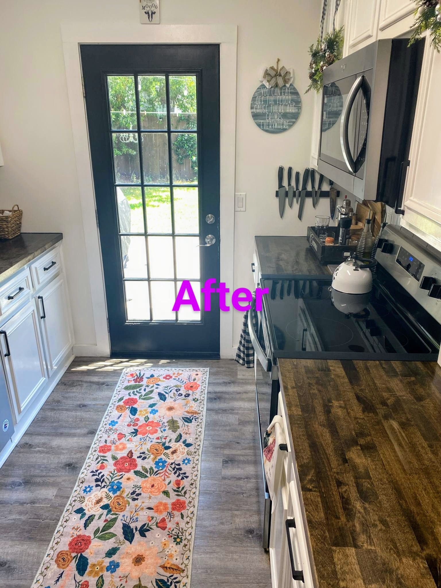 Kitchen renovation: floral rug, black door, white cabinets, black countertops, and stove.