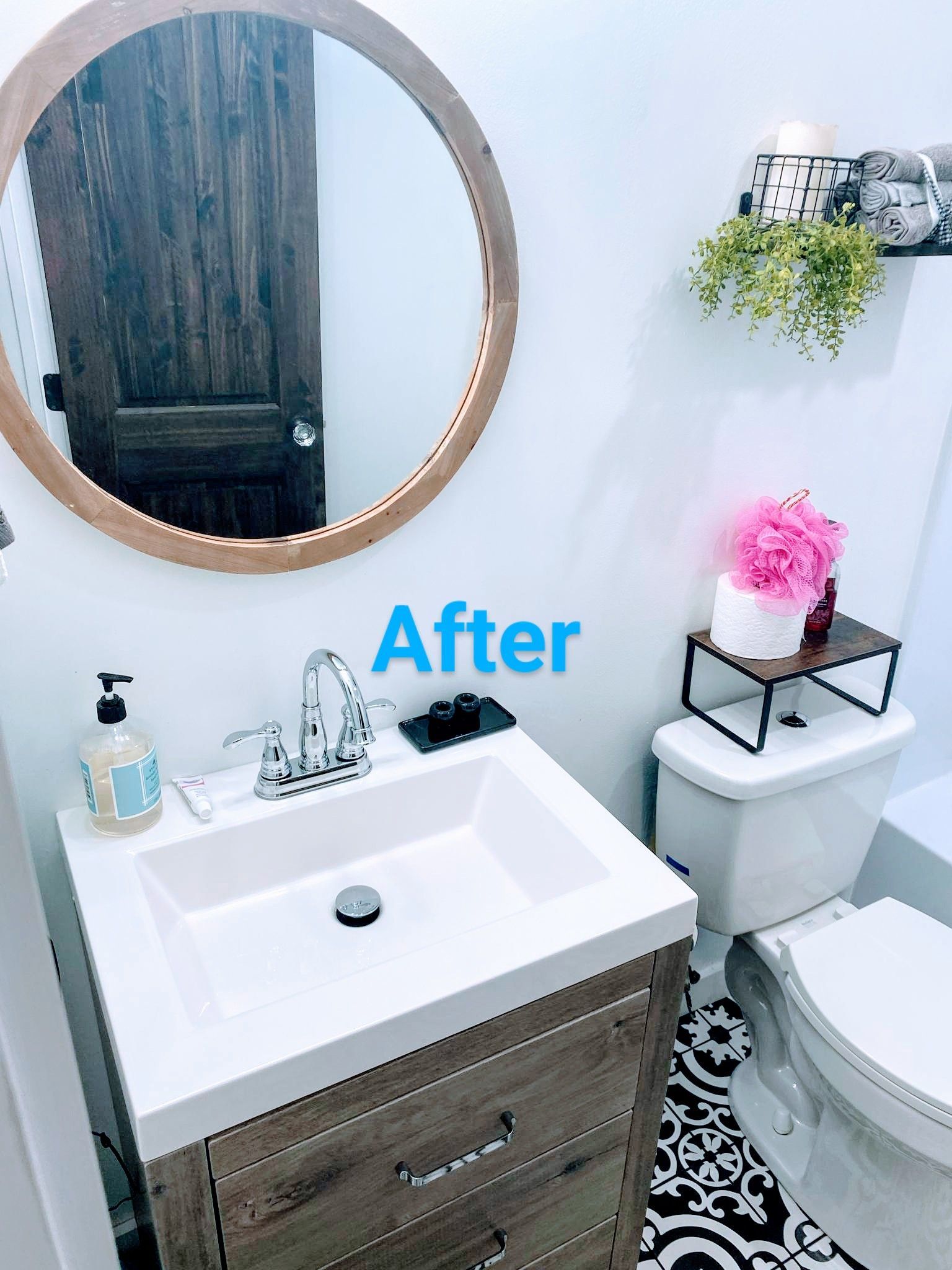 Bathroom with a wooden vanity, round mirror, and black and white patterned floor.