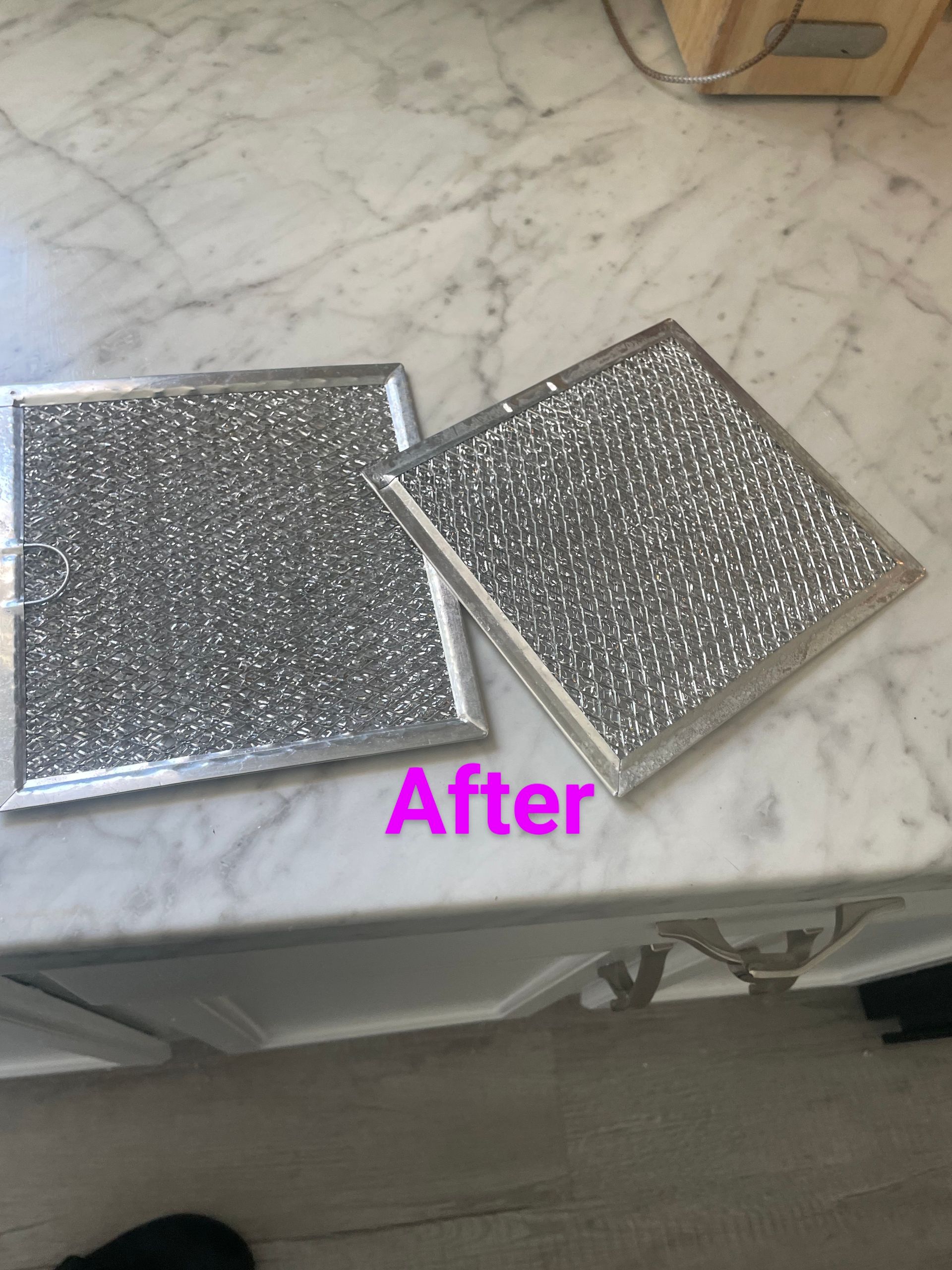 Two clean silver range hood filters on a white countertop, labeled 
