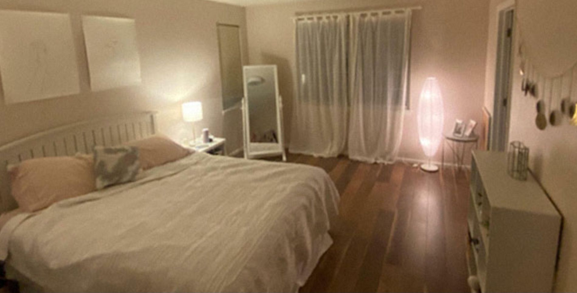 A bedroom with a bed , dresser , mirror and curtains.