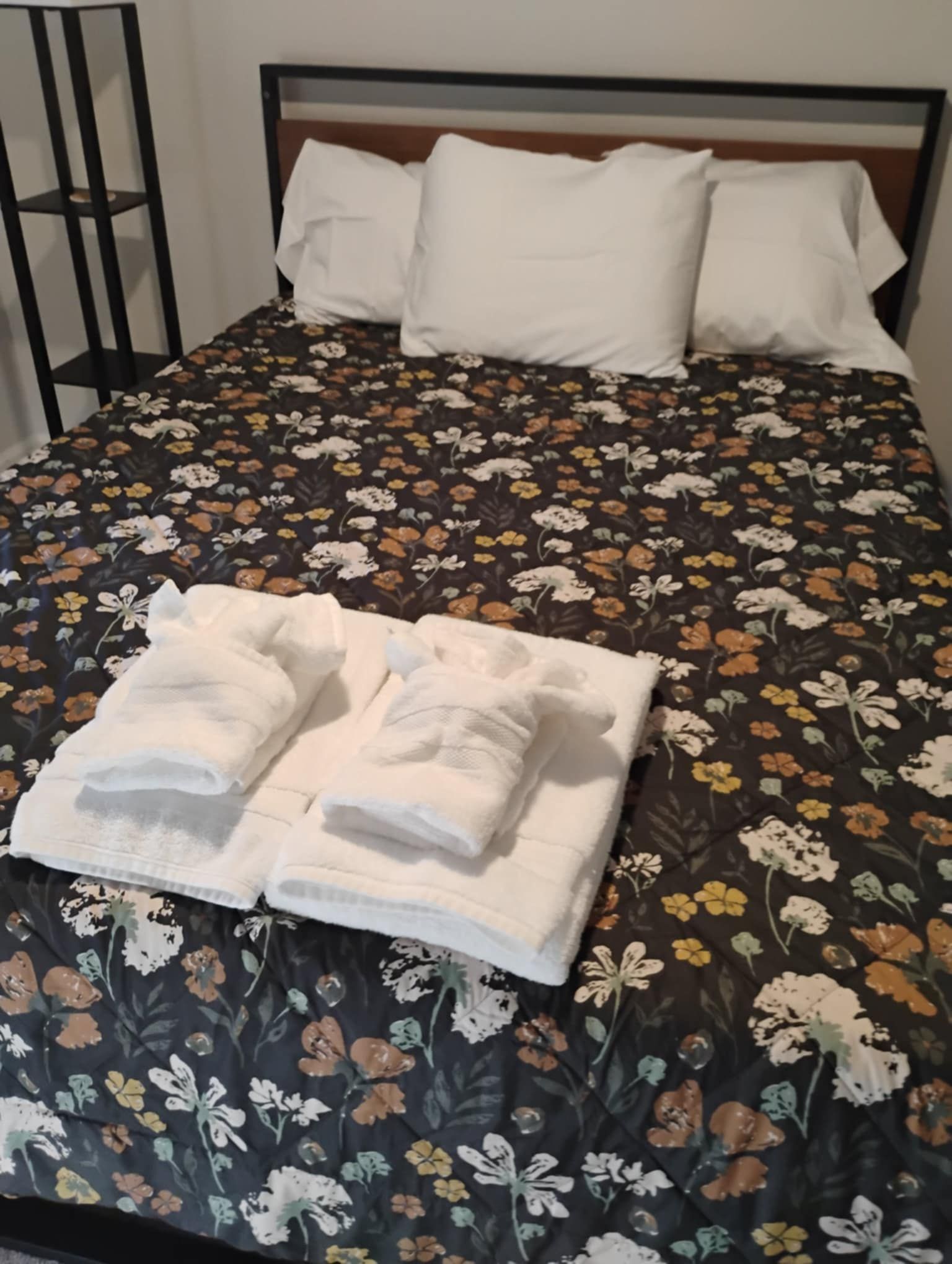 A bed with a floral comforter and towels on it