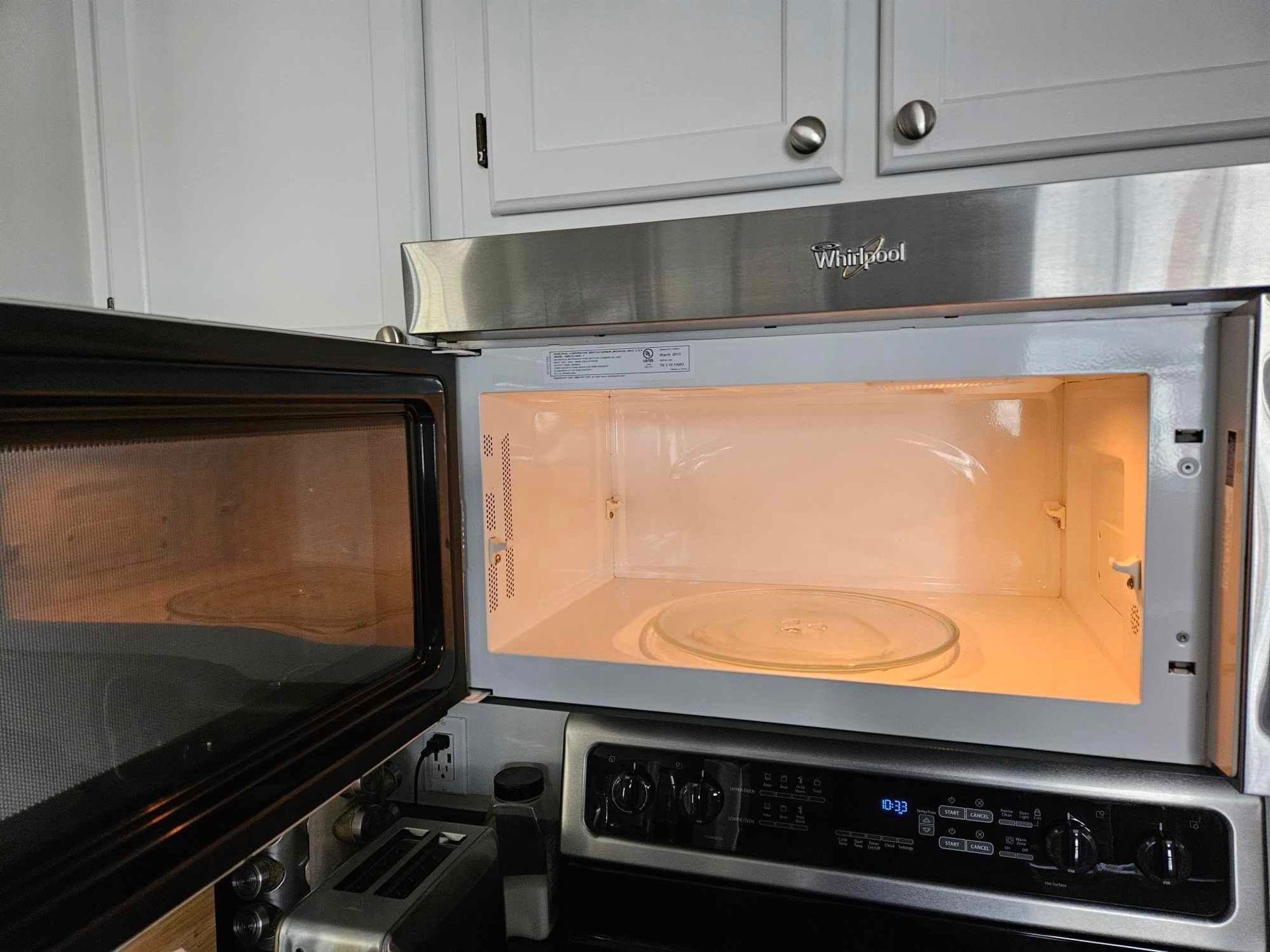 An open microwave oven in a kitchen with the door open.