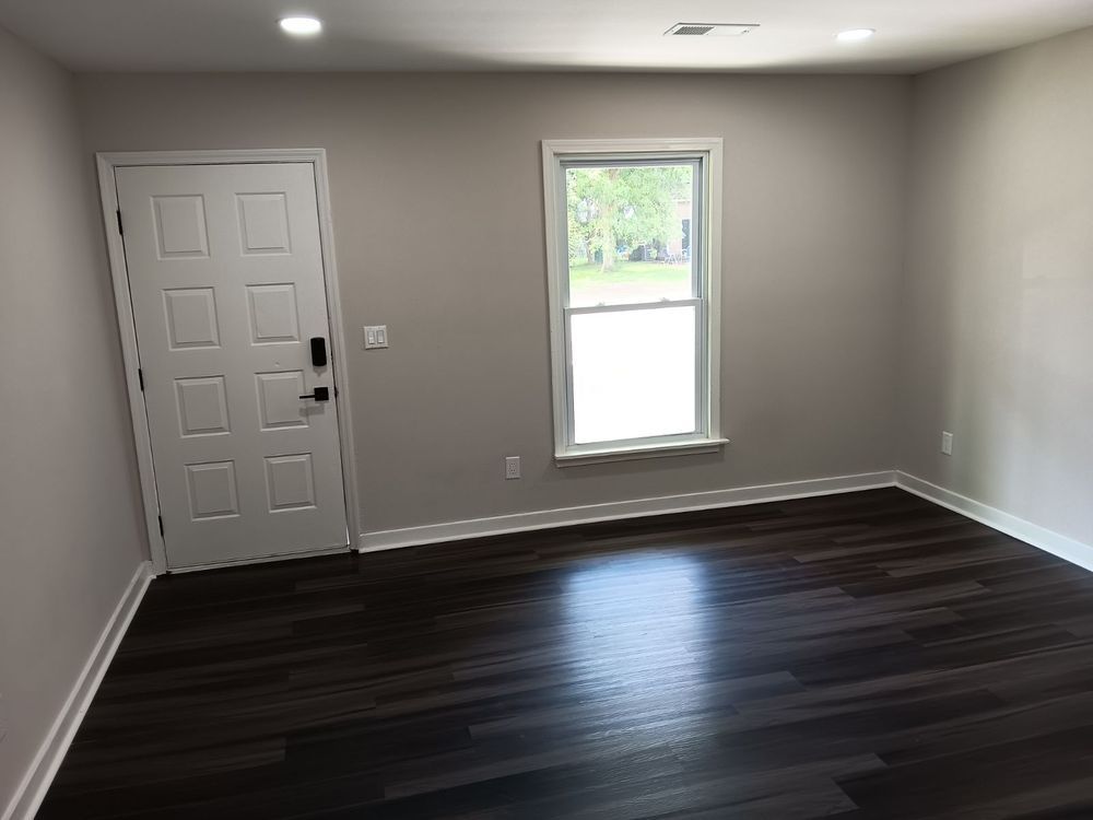 An empty room with a door and a window.