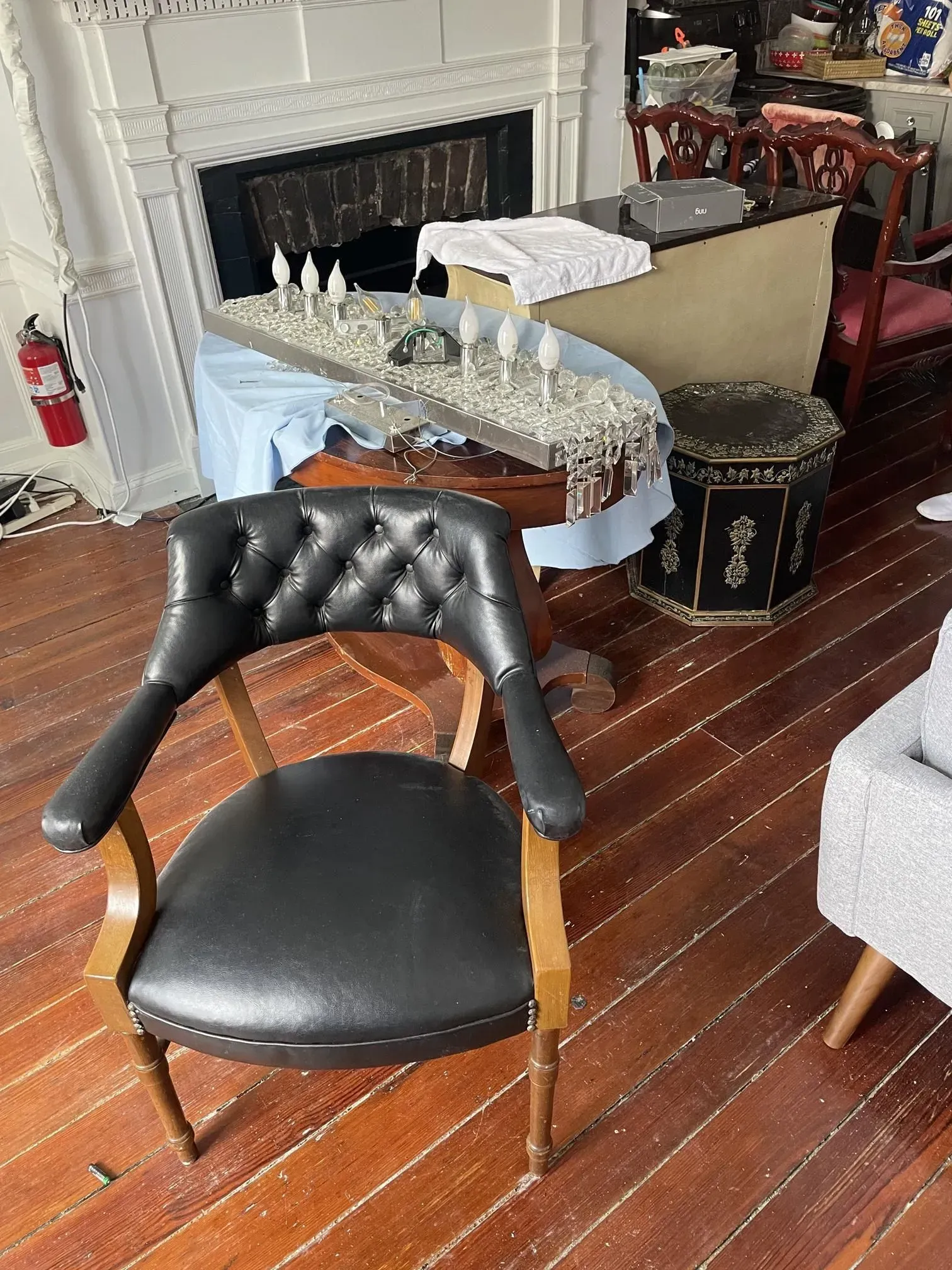 Black leather armchair in front of a room with assorted furniture and a fireplace.