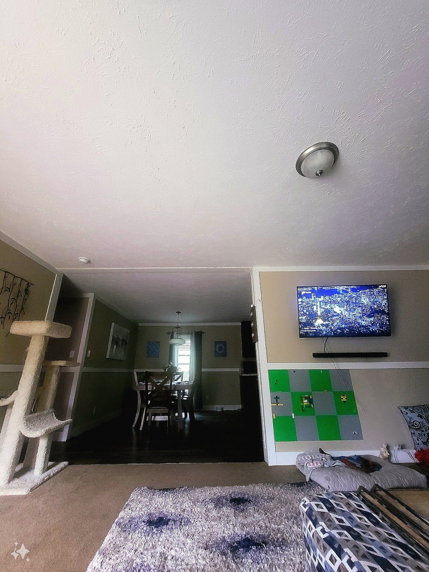 A living room with a cat tree and a flat screen tv on the wall.