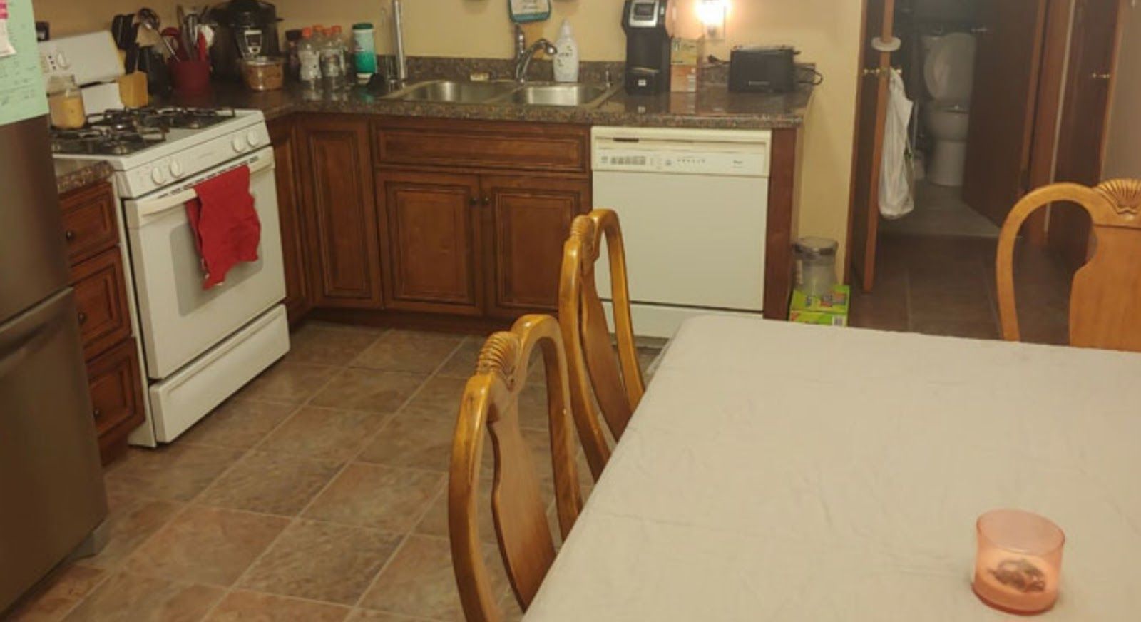 A kitchen with a table , chairs , stove and dishwasher.