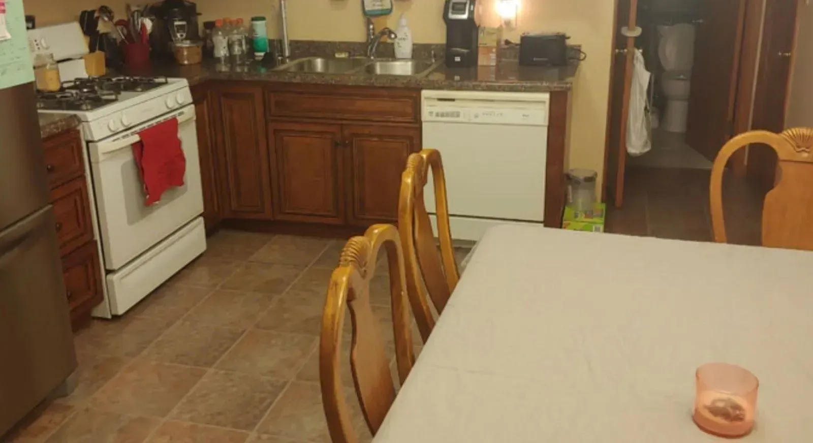 Kitchen with cabinets, stove, dishwasher, dining table with chairs, and a doorway.
