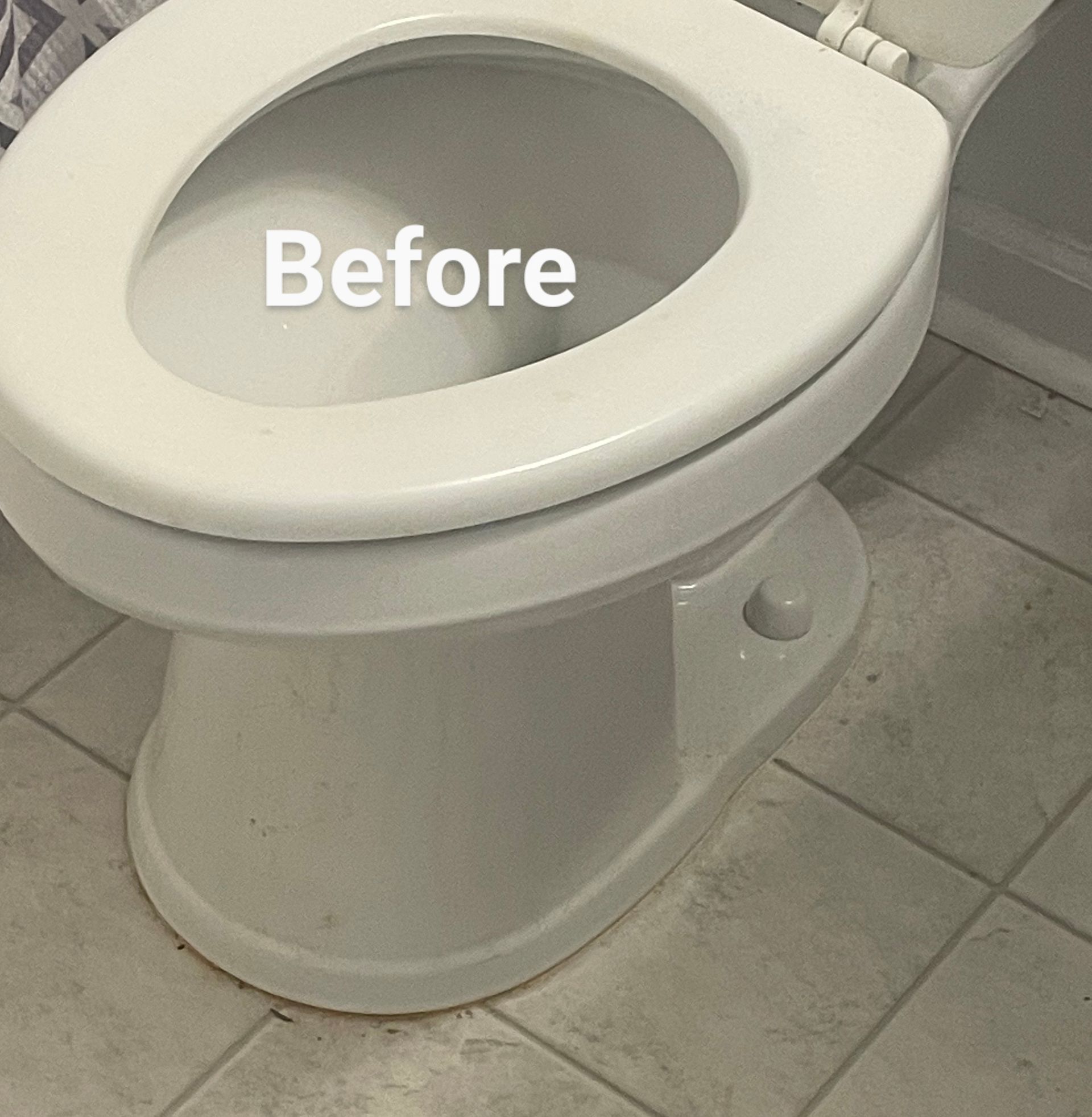 White toilet with seat up, on tiled floor; 