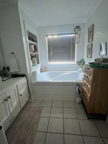 A bathroom with a tub , sink , mirror and window.