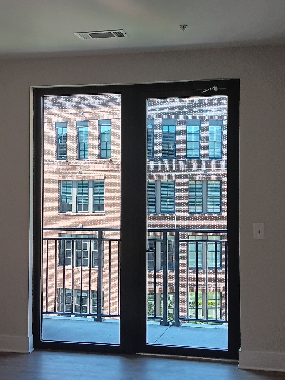 An empty room with a balcony and a brick building in the background