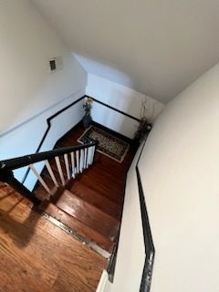 A wooden staircase with a black railing leading up to the second floor of a house.