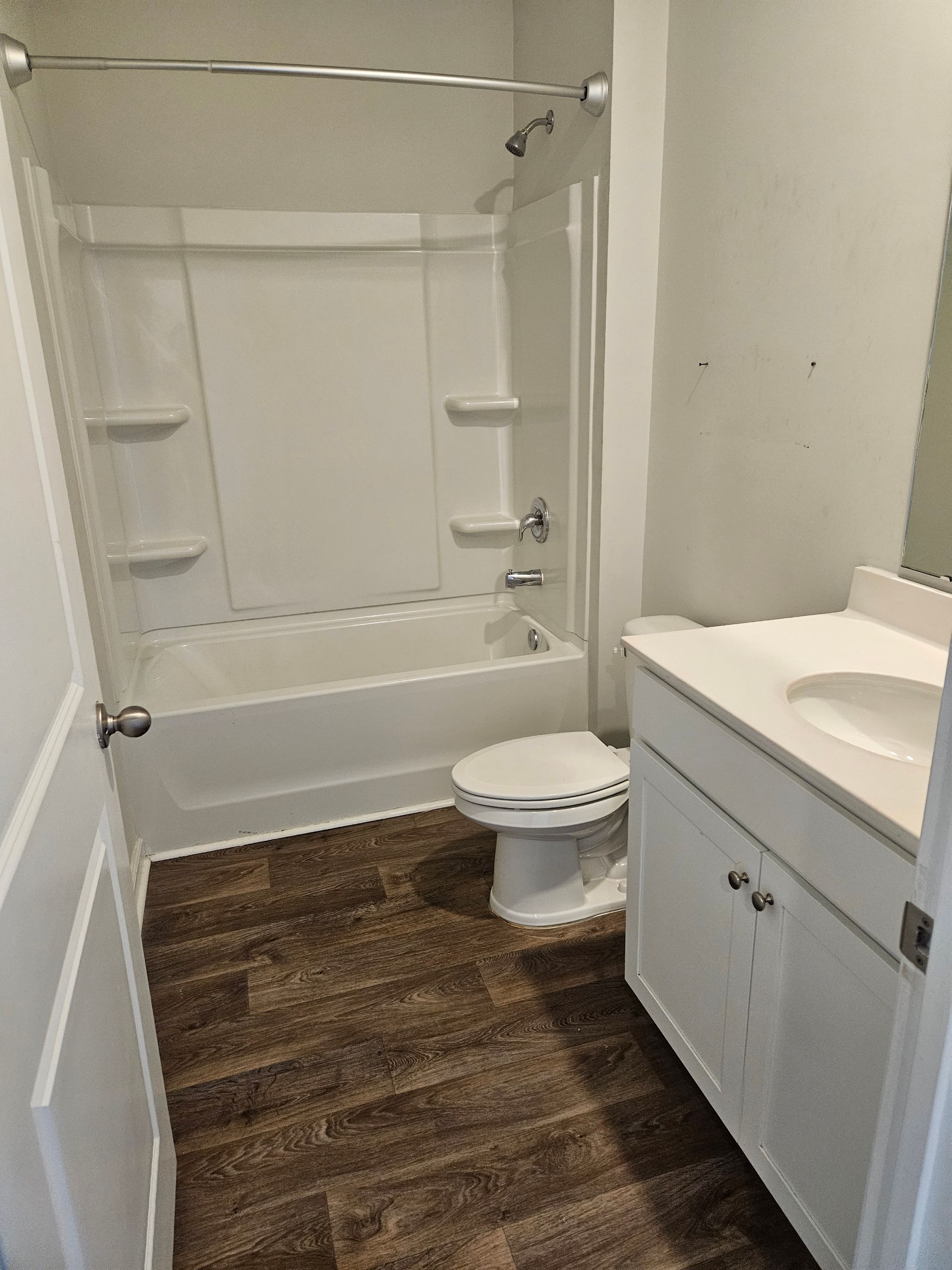 A bathroom with a tub , toilet , sink and mirror.