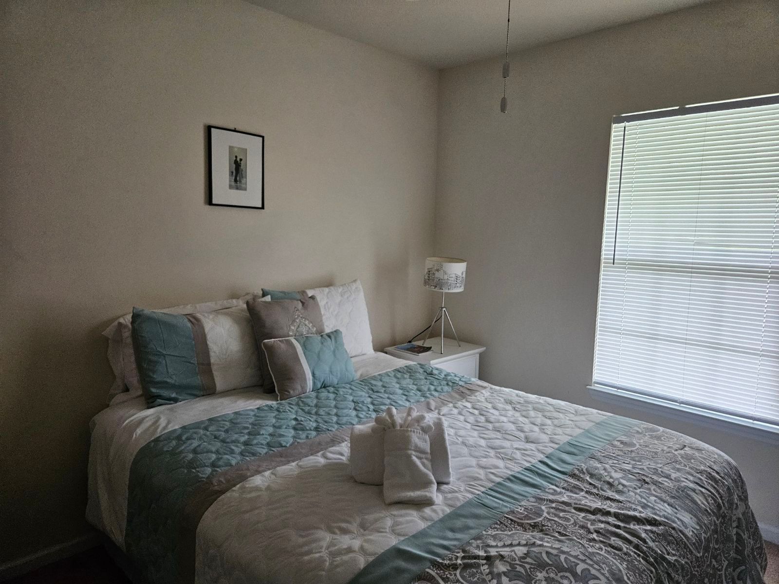 A bedroom with a bed and a window with blinds.