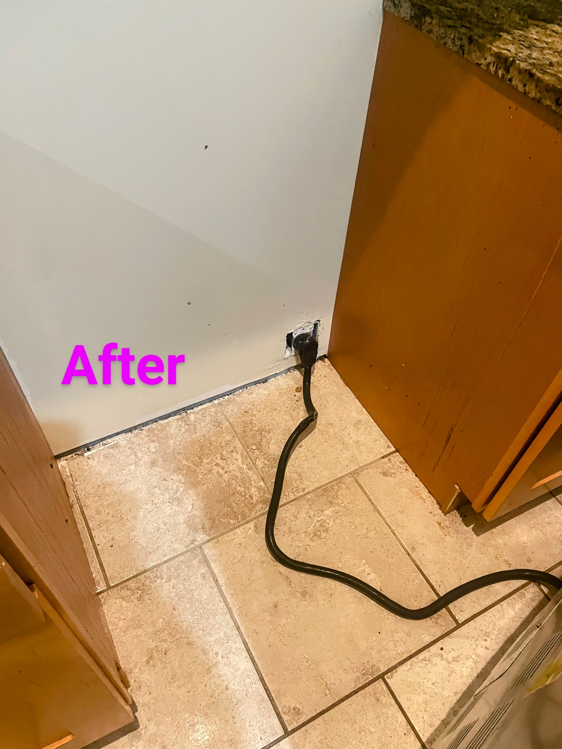 Black electrical cord near wall and cabinets in a kitchen setting.