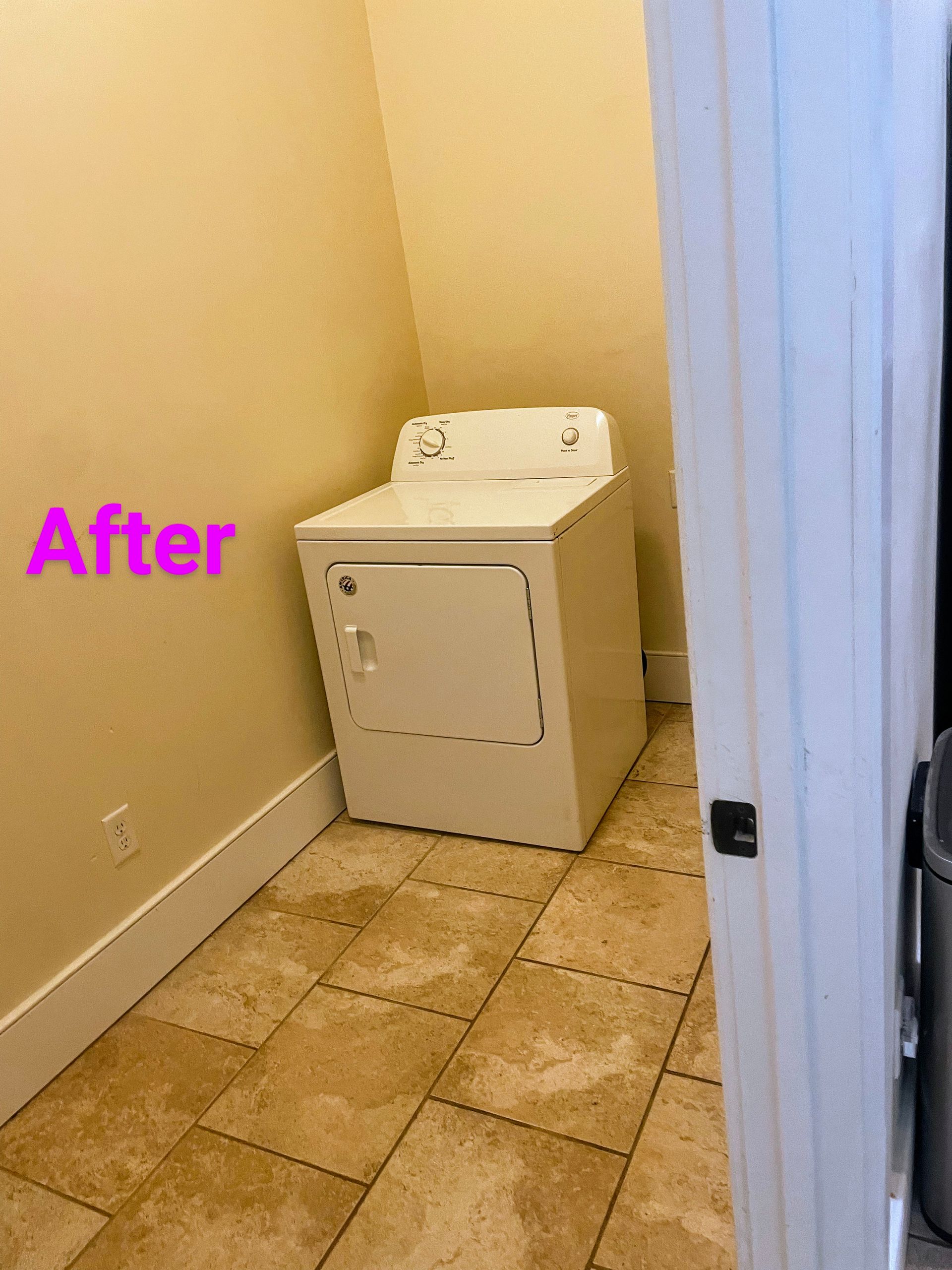 Laundry room: white dryer against yellow wall, tan tile floor. 