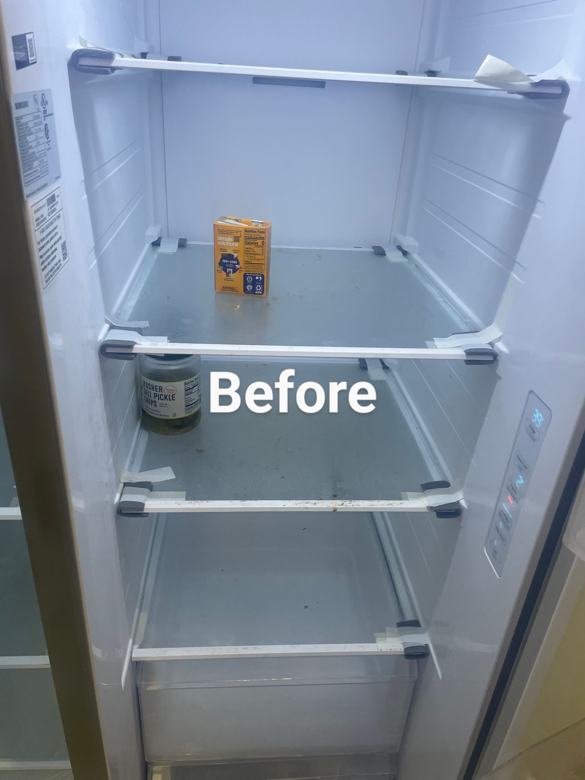 Empty refrigerator interior with a carton and jar of food before cleaning.