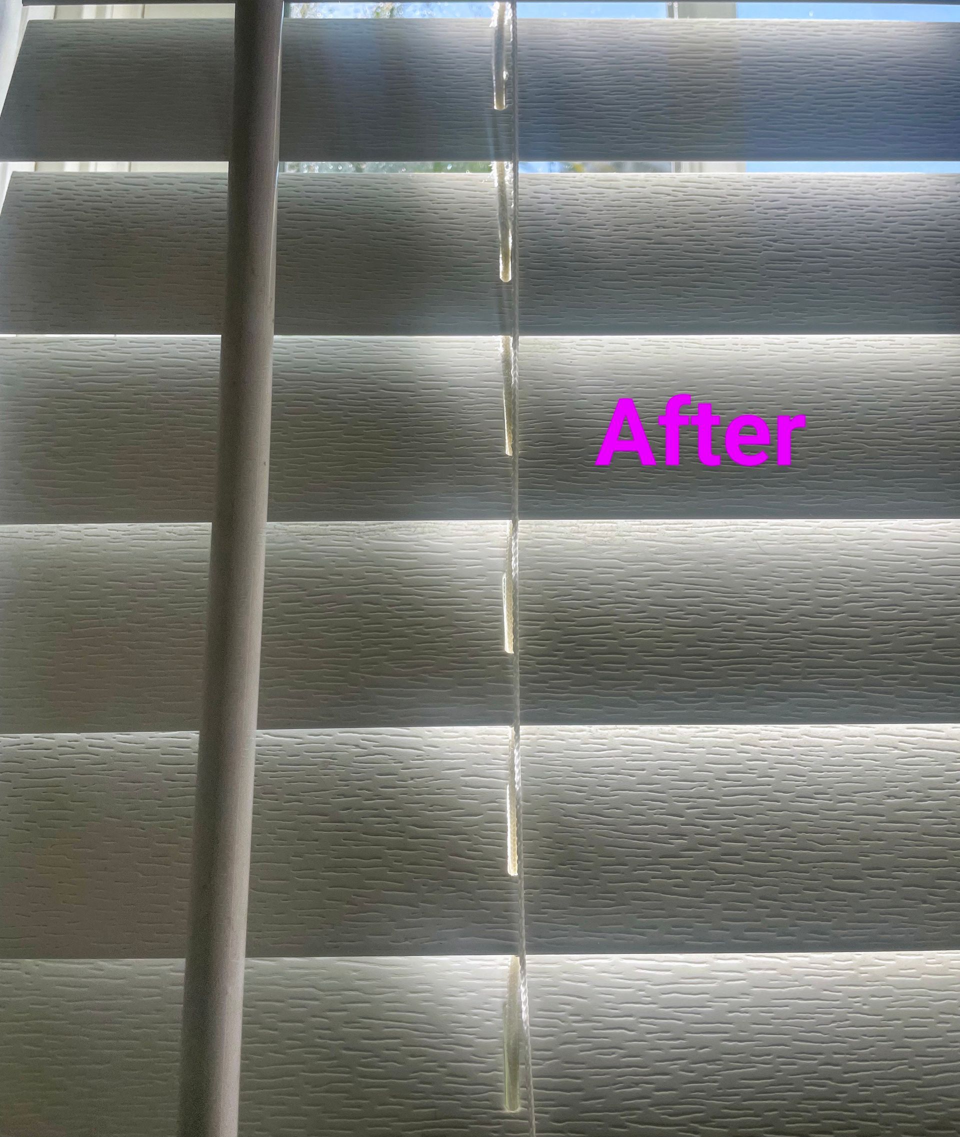 Blinds, partially open, letting in light. The word 