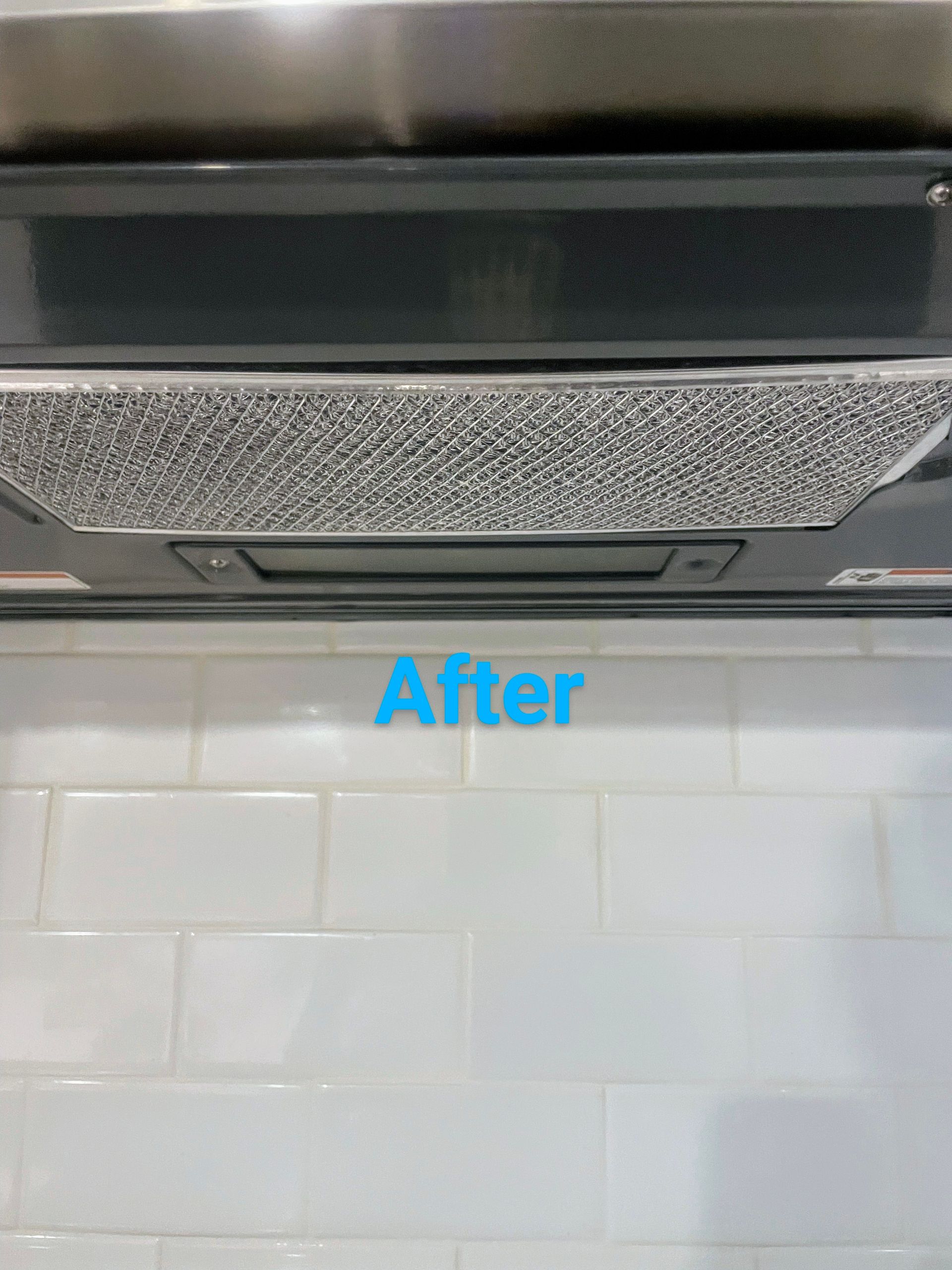 Clean range hood over white tiled backsplash; 
