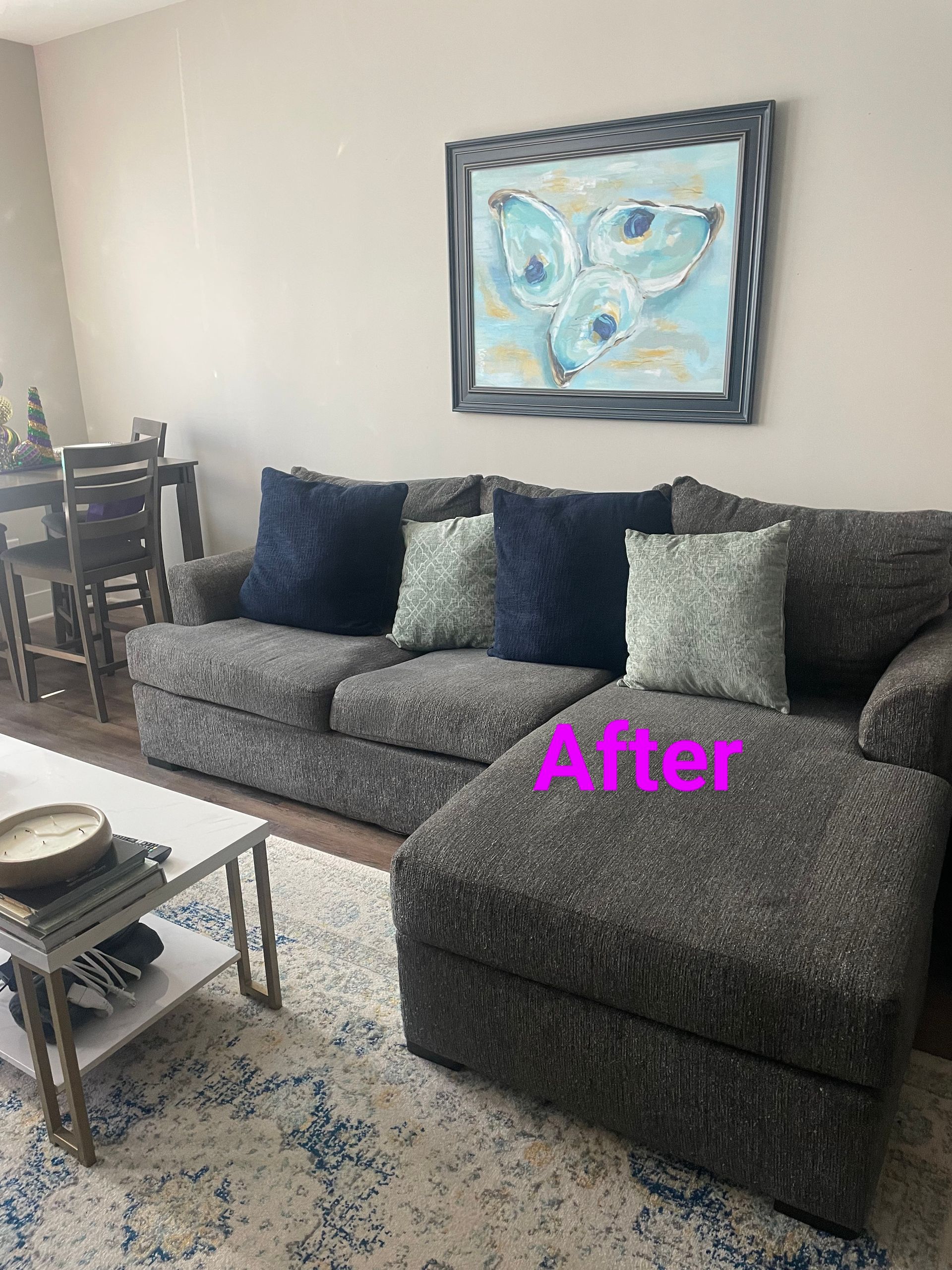 Living room with gray couch, blue and green pillows, art, coffee table, and rug.
