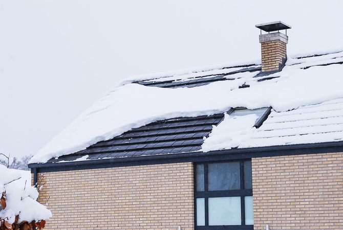 Une maison en brique avec de la neige sur le toit et une cheminée