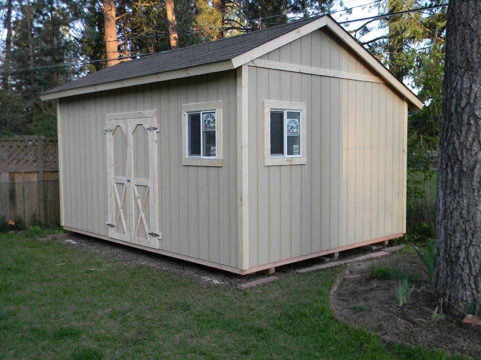 A small shed with a roof and two windows in a backyard