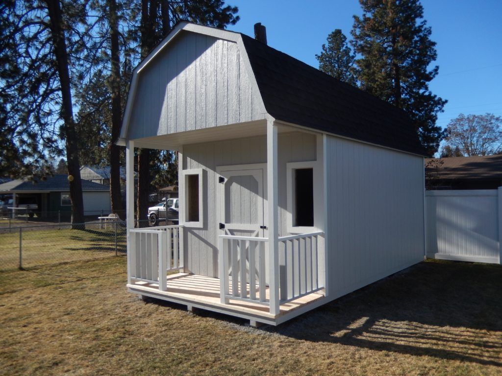 A white shed with a porch and a black roof