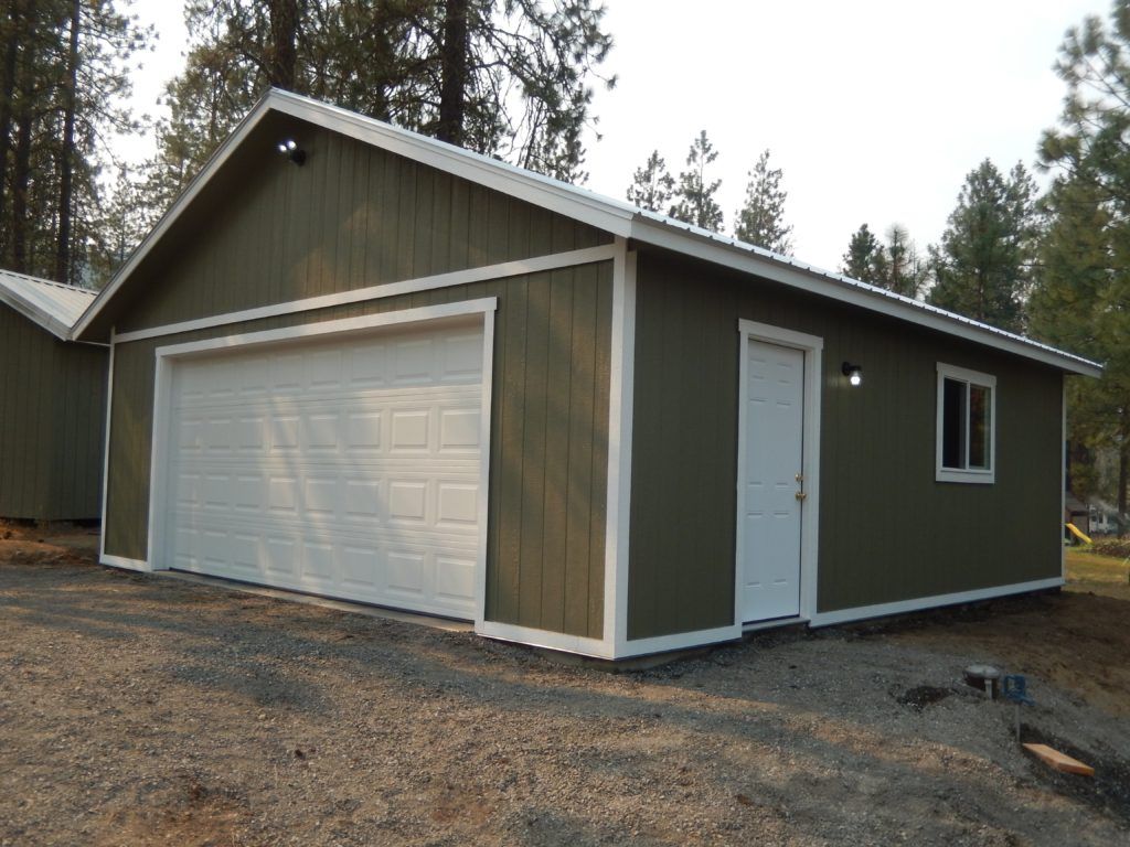 A green garage with a white door and a window