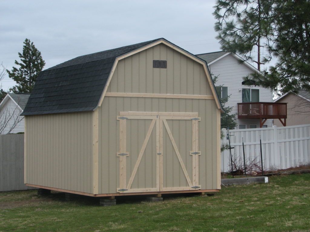 A barn with a black roof is in the middle of a grassy field