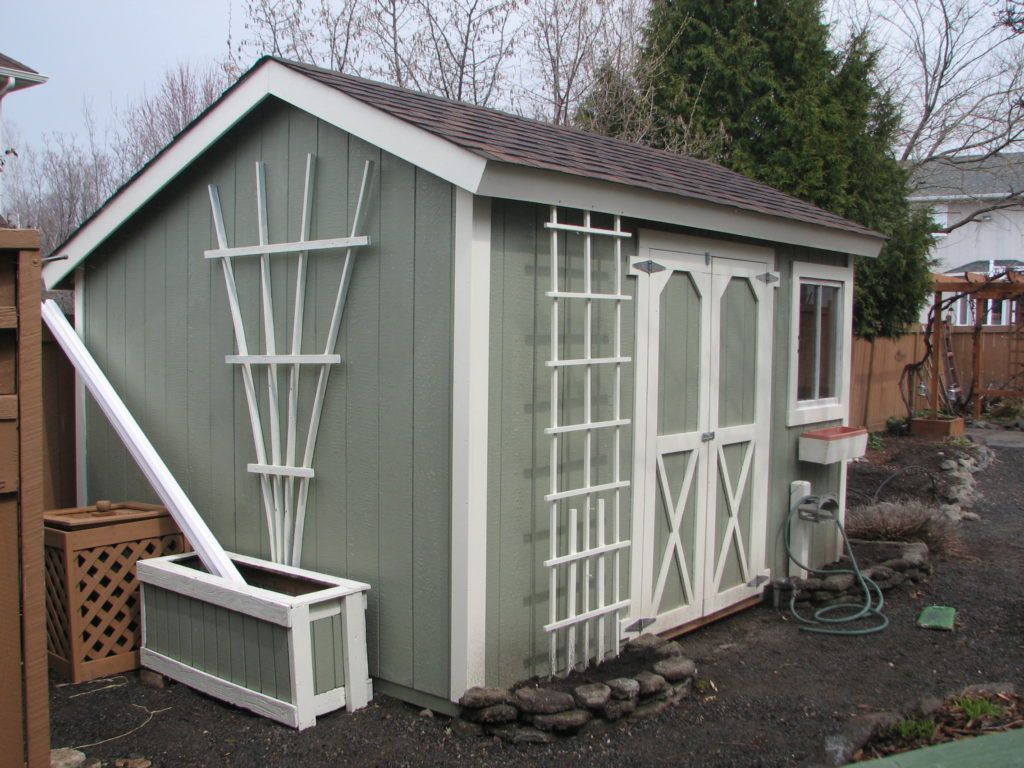 A green and white shed with a trellis on the side