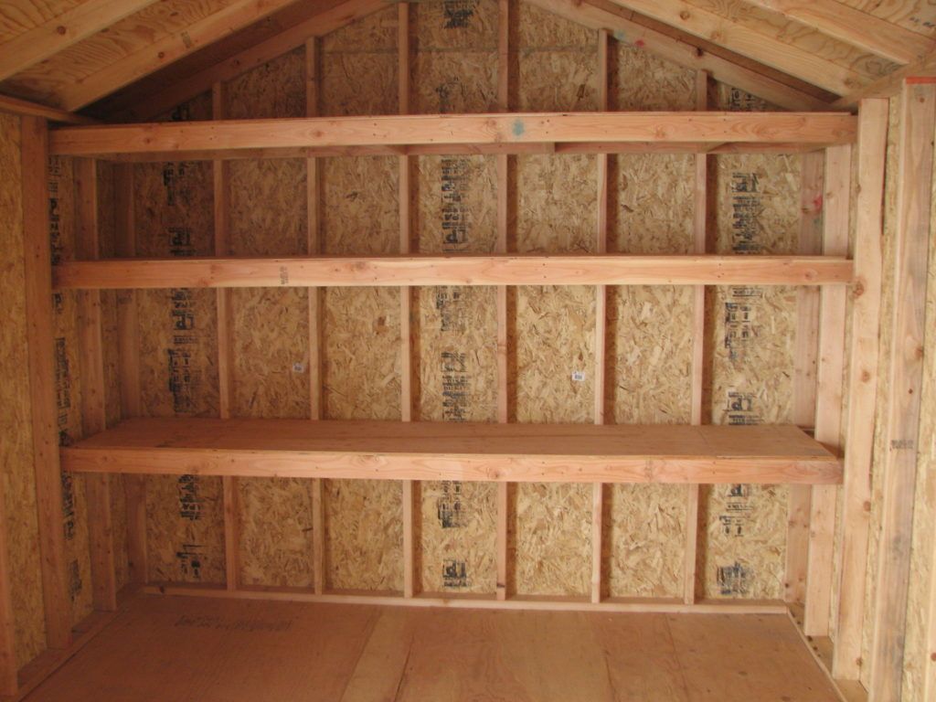 The inside of a wooden shed with shelves and a roof