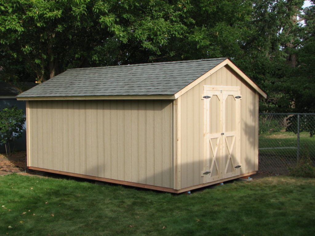 A shed with a gray roof is sitting in the grass