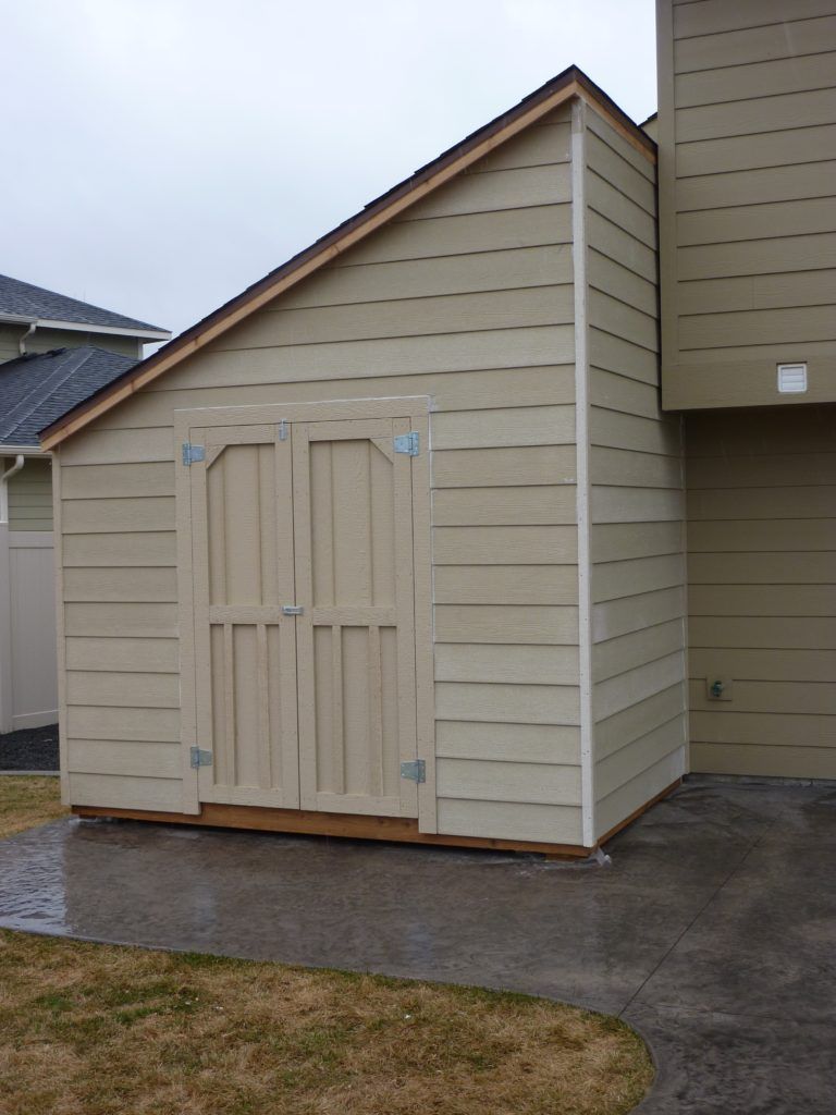 A shed with a slanted roof is next to a house