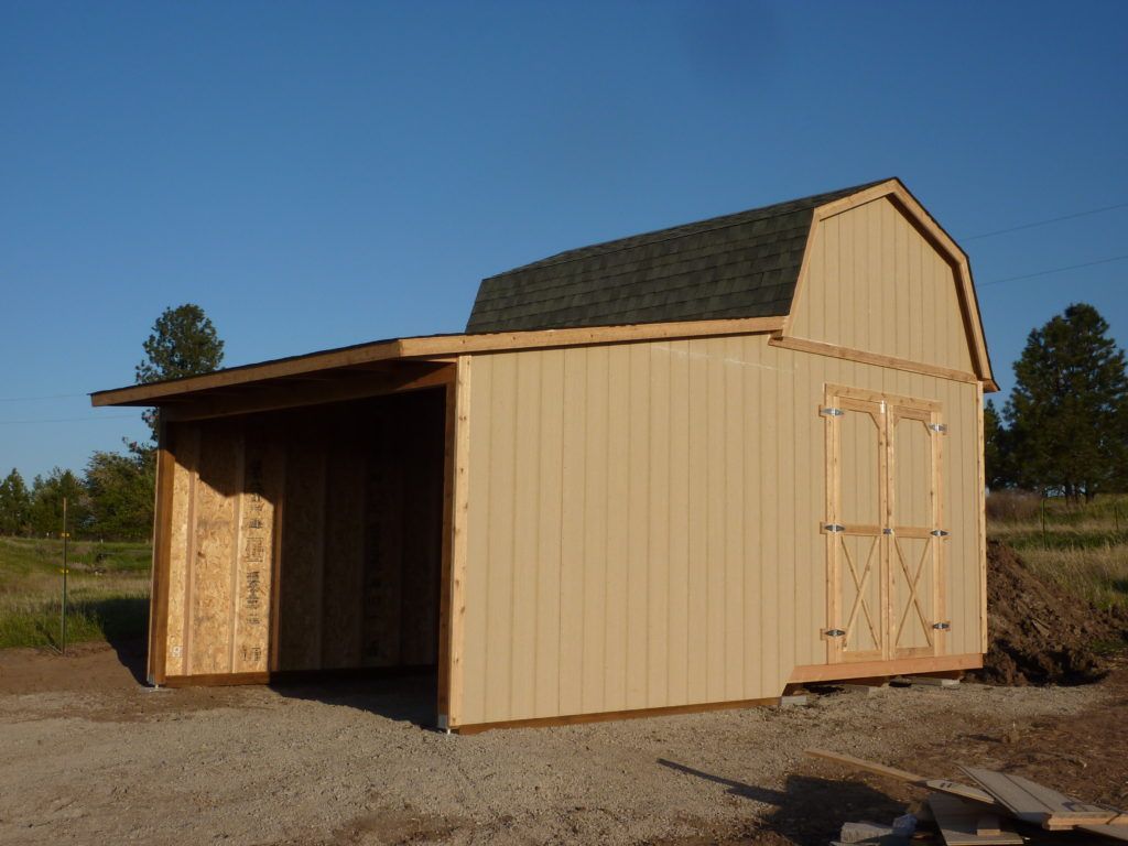 A wooden barn with a shed attached to it
