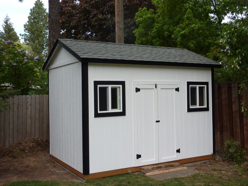 A white shed with black trim and two windows