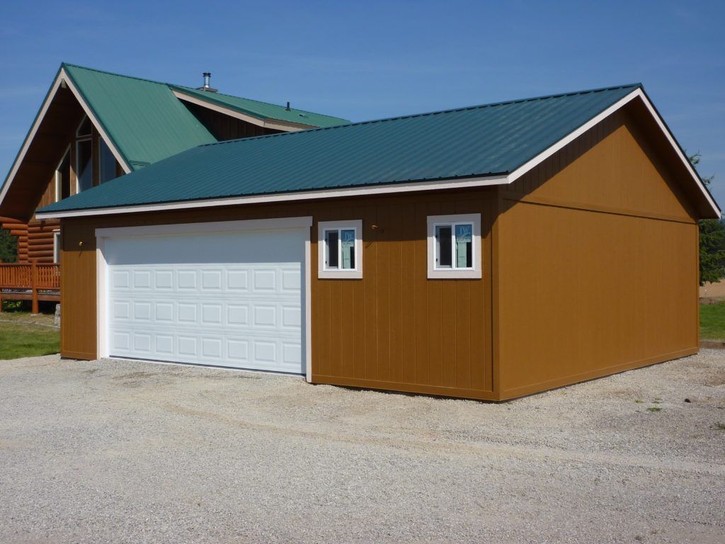 A brown garage with a green roof and white doors