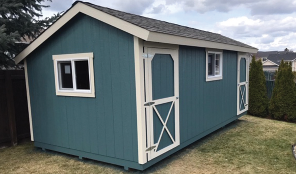 A blue and white shed with a roof is sitting in the grass.