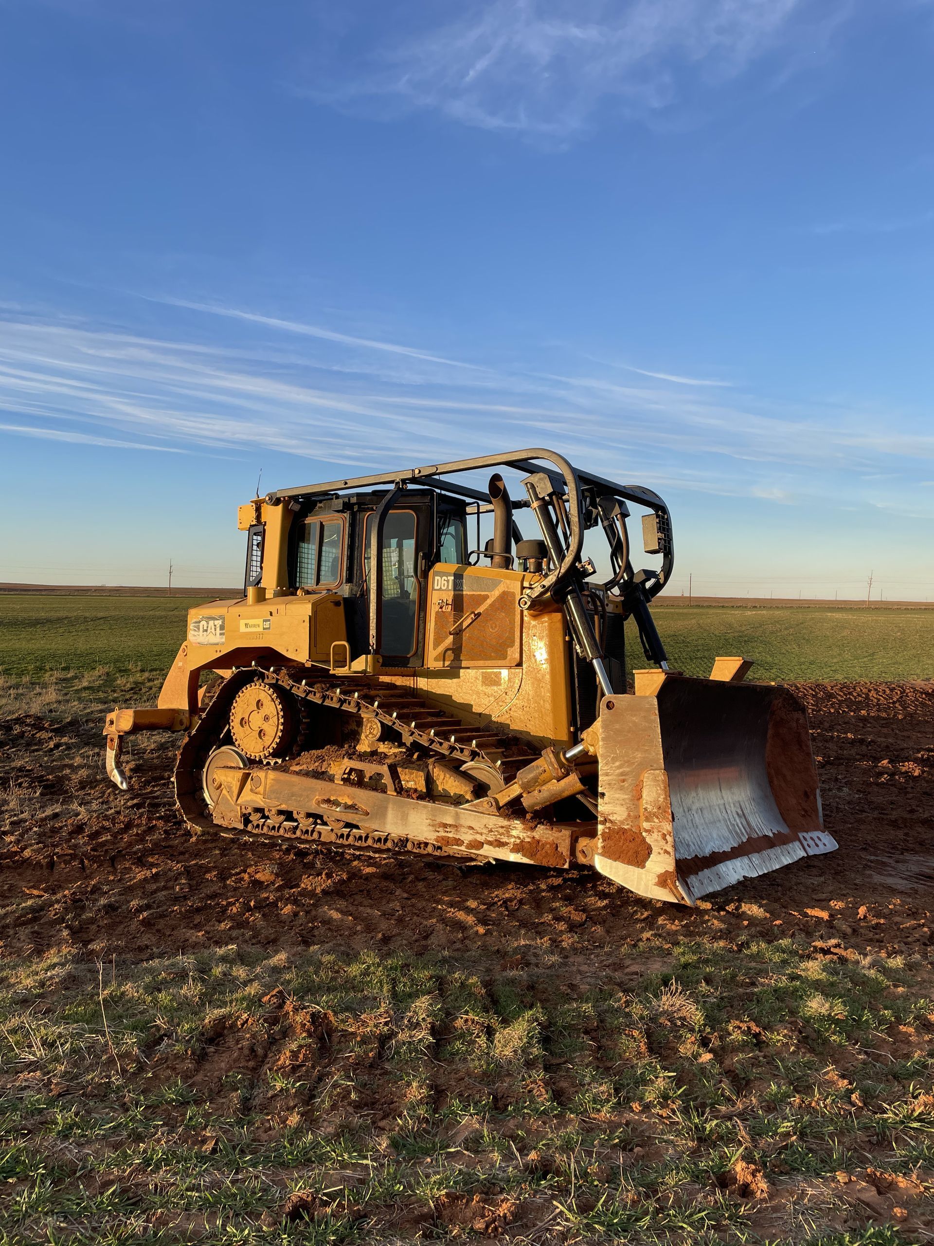 Yellow bulldozer on muddy ground, blue sky background.