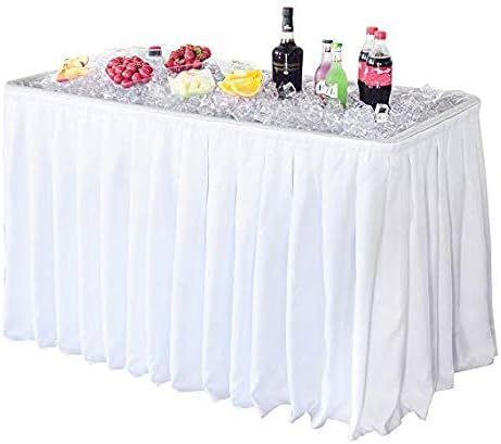 White buffet table with food and drinks chilled on ice, draped with a white pleated skirt.