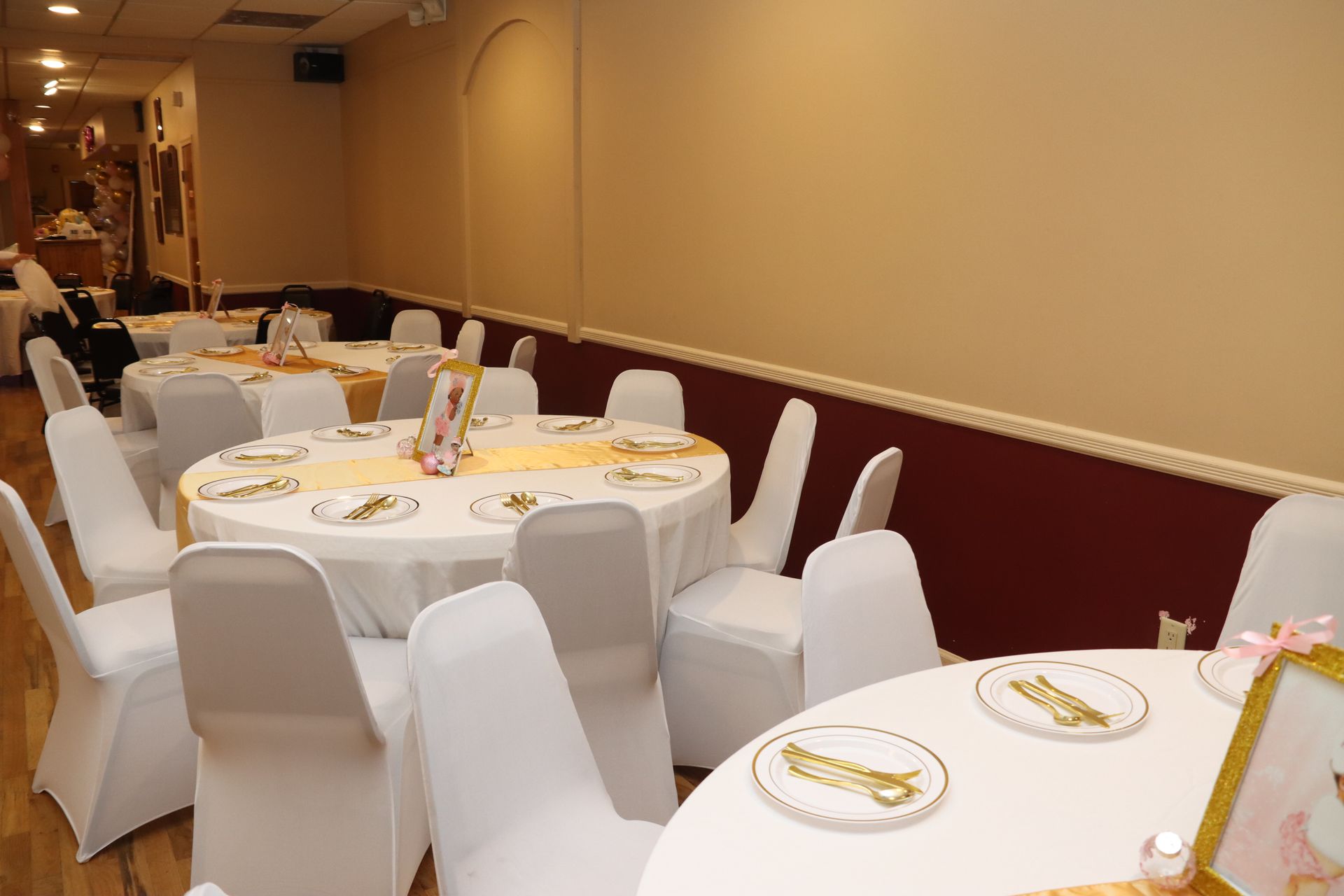 Round tables set for a formal event inside a room, each covered in white tablecloths with matching chair covers.