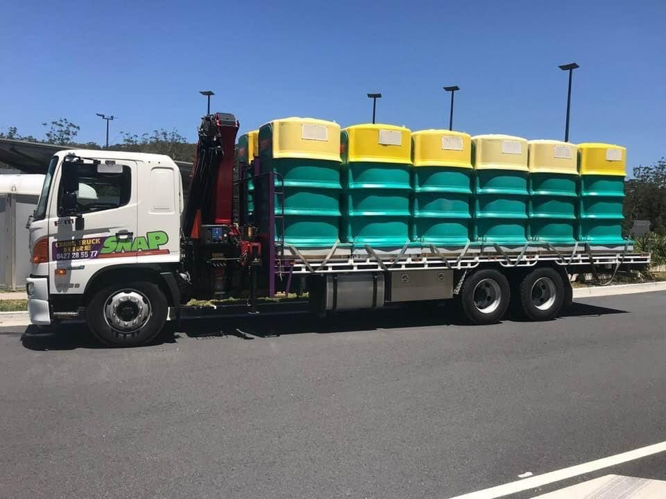 A White Truck With A Crane Is Carrying A Stack Of Green And Yellow Containers — Snap Crane Truck Hire in Tamworth, NSW