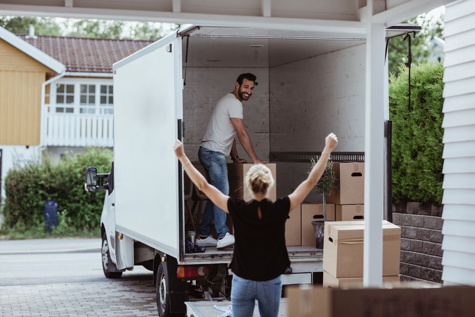 Woman cheering, man in a truck unloading boxes, moving day.