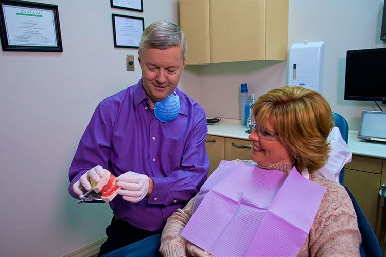 Dr Ian Malloch showing a teeth model to a woman