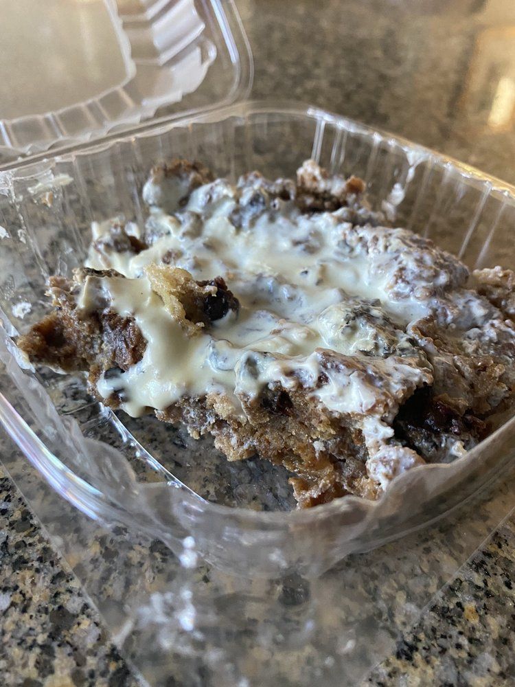 Brown, textured food with white sauce in a clear plastic container.